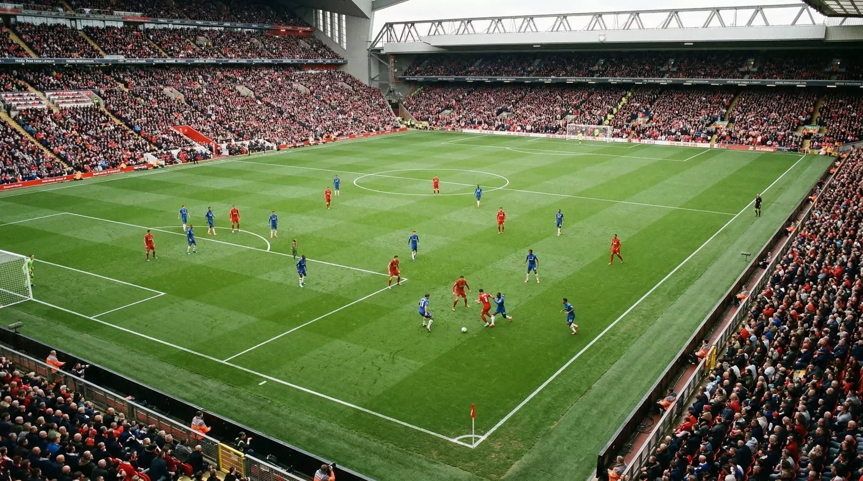 Campo de fútbol de la Premier League con líneas de juego y grada al fondo durante un partido diurno